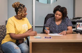 Two women sitting at an office table,signing documents